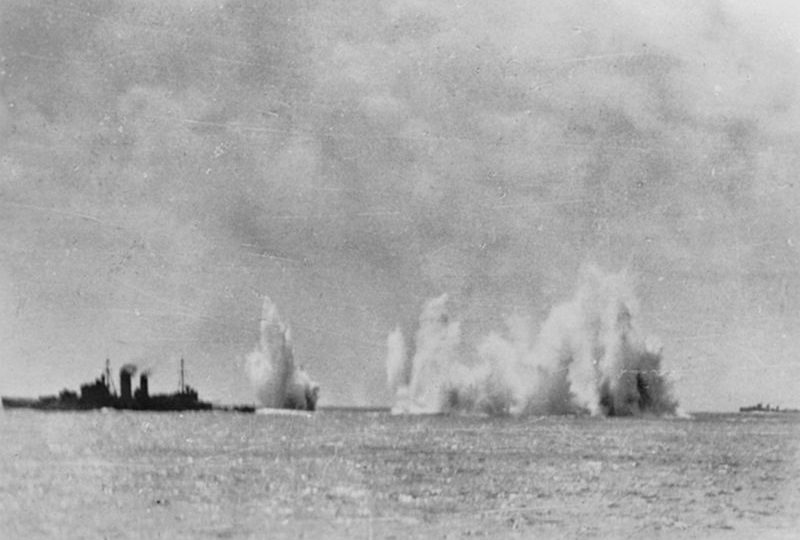 The Royal Navy cruiser HMS Exeter (68) and the Australian cruiser HMAS Hobart (D63) under aerial attack by Japanese aircraft in seas of South East Asia. A Dutch destroyer is visible at right. Most probably this image was taken as the ship was passing through the Gaspar Straights, Indonesia, 14-15 February 1942. Photo: Wikimedia Commons
