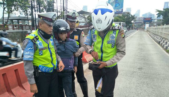 Police officers apprehending a motorcyclist for alleged possession of marijuana in South Jakarta on January 3, 2018. Photo: Facebook