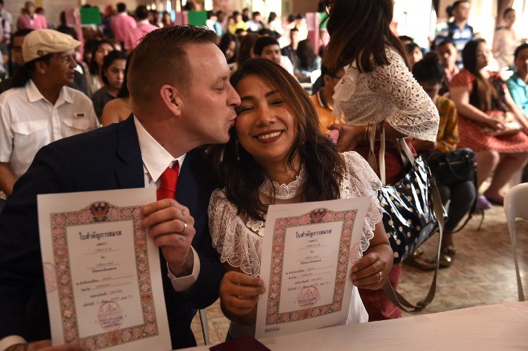 A Thai woman and a British man hold up their marriage certificates on Valentine’s Day at the central post office in the Bang Rak, or “Love Village”, district in Bangkok on February 14, 2018. Photo: AFP