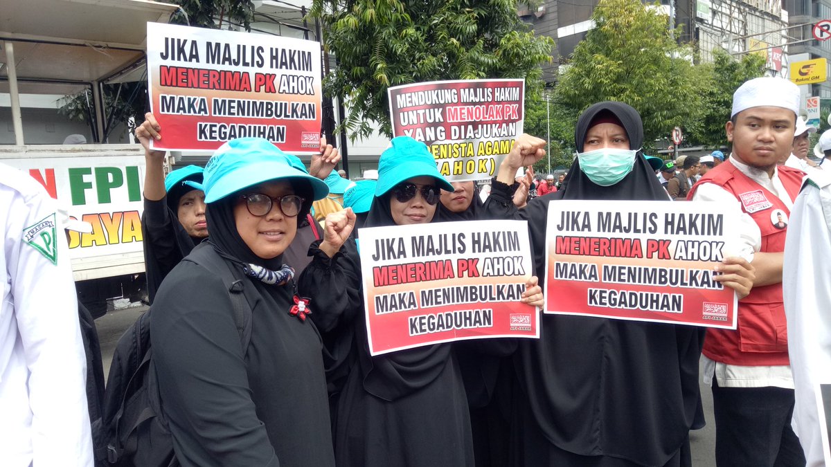 Protesters at the first session of former Jakarta Governor Basuki “Ahok” Tjahaja Purnama’s judicial review (PK) on Feb 26, 2017. Their sigsn say “If the judges accept Ahok’s PK then it will caused an uproar”. Photo: Twitter / @Jawara_B411