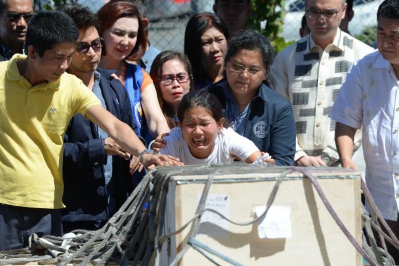 Jessica (C), sister of Filipina worker Joanna Demafelis whose body was found inside a freezer in Kuwait, cries in front of a wooden casket containing her sister’s body shortly after its arrival at the international airport in Manila, Feb. 16, 2018. Photo: Ted Aljibe/ AFP