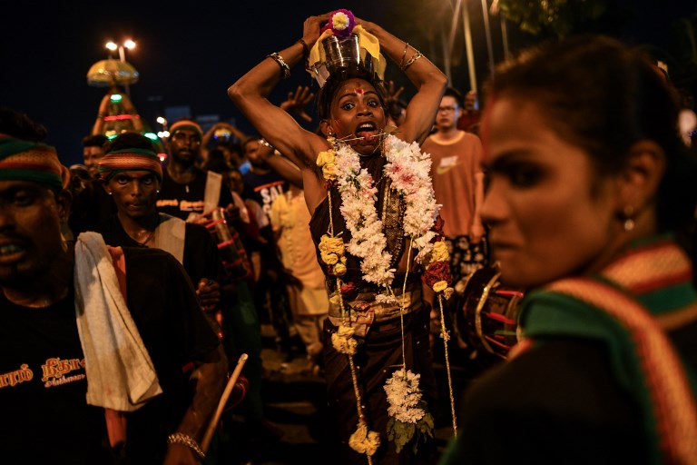 An ethnic-Malaysian Hindu devotee (C) dances in a state of trance as she makes her way towards the Batu caves temple during the Thaipusam festival celebrations in Kuala Lumpur on January 31, 2018. / AFP PHOTO / Manan Vatsyayana