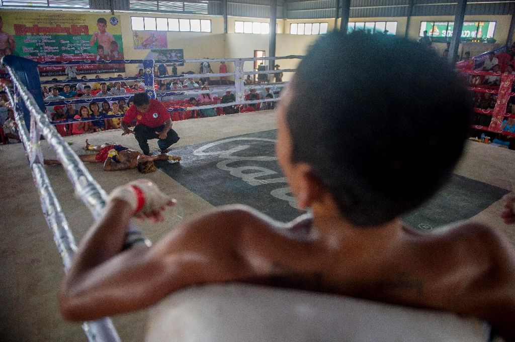 In this photograph taken on March 27, 2018, Zwe Maung Maung (R) watches from the corner while the referee counts down after Zwe knocked out opponent Saw Maung Lay (bottom L) during a ground-breaking Lethwei competition marking Armed Forces Day in the town of Maungdaw in Rakhine State. / Phyo Hein KYAW / AFP /