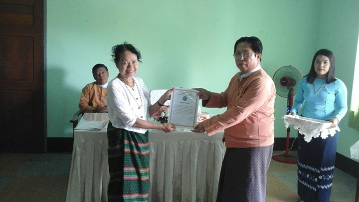 Mon State’s Bamar ethnic affairs minister U Shwe Myint presents Daw Khin Win with a certificate of honor in exchange for the ancient ‘Pyu’ beads in Mawlamyine. Photo: MOI