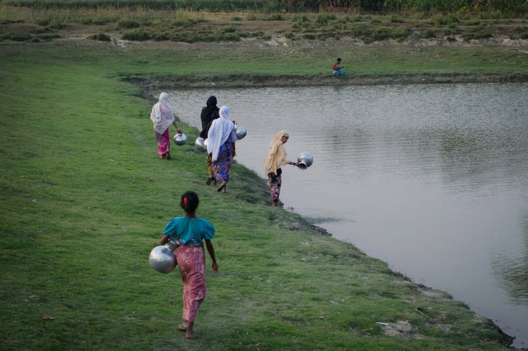 This photograph taken on March 10, 2018, Rohingya women collects water from a pond at Shan Taung village in the outskirt of Mrauk U township located in Rakhine State close to Bangladesh border. / AFP PHOTO / Phyo Hein KYAW