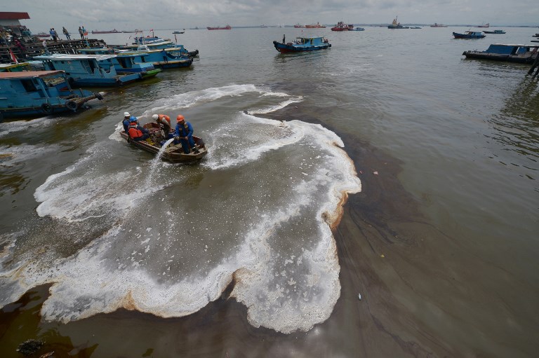 This picture taken on March 31, 2018 shows Indonesian workers trying to clean an oil spill from the sea in Balikpapan.
An oil spill off Borneo island that led to five deaths and the declaration of a state of emergency was caused by a ruptured undersea pipe, Indonesia’s national oil company Pertamina said on April 4. / AFP PHOTO / ARIDJWANA