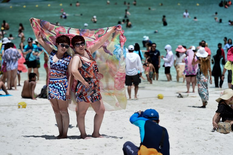 This photo taken on April 9, 2018 shows tourists having their photo taken by a guide on Maya Bay, on the southern Thai island of Koh Phi Phi. Photo: AFP