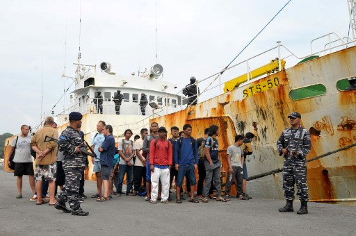 This picture taken on April 7, 2018 shows Indonesian military guarding the crew next to a seized alleged “slave ship” at the naval port of Sabang, following a dramatic high seas chase before the boat was captured some 60 miles (95 kilometres) from Weh Island in Aceh province.
Indonesia seized the alleged “slave ship” following a dramatic high seas chase sparked by an Interpol alert after the vessel escaped capture in China and Mozambique, authorities said on April 10. / AFP PHOTO
