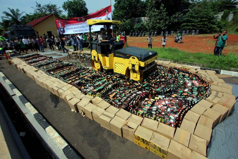 Indonesian police destroy thousands of bottles of illegal homemade alcohol during a public display in South Tangerang, outside Jakarta on April 13, 2018.
Thousands of booze bottles were destroyed by Indonesian police on Friday in a dramatic show as they crack down on bootleg alcohol blamed for killing about 100 people in recent weeks.
 / AFP PHOTO / DEMY SANJAYA