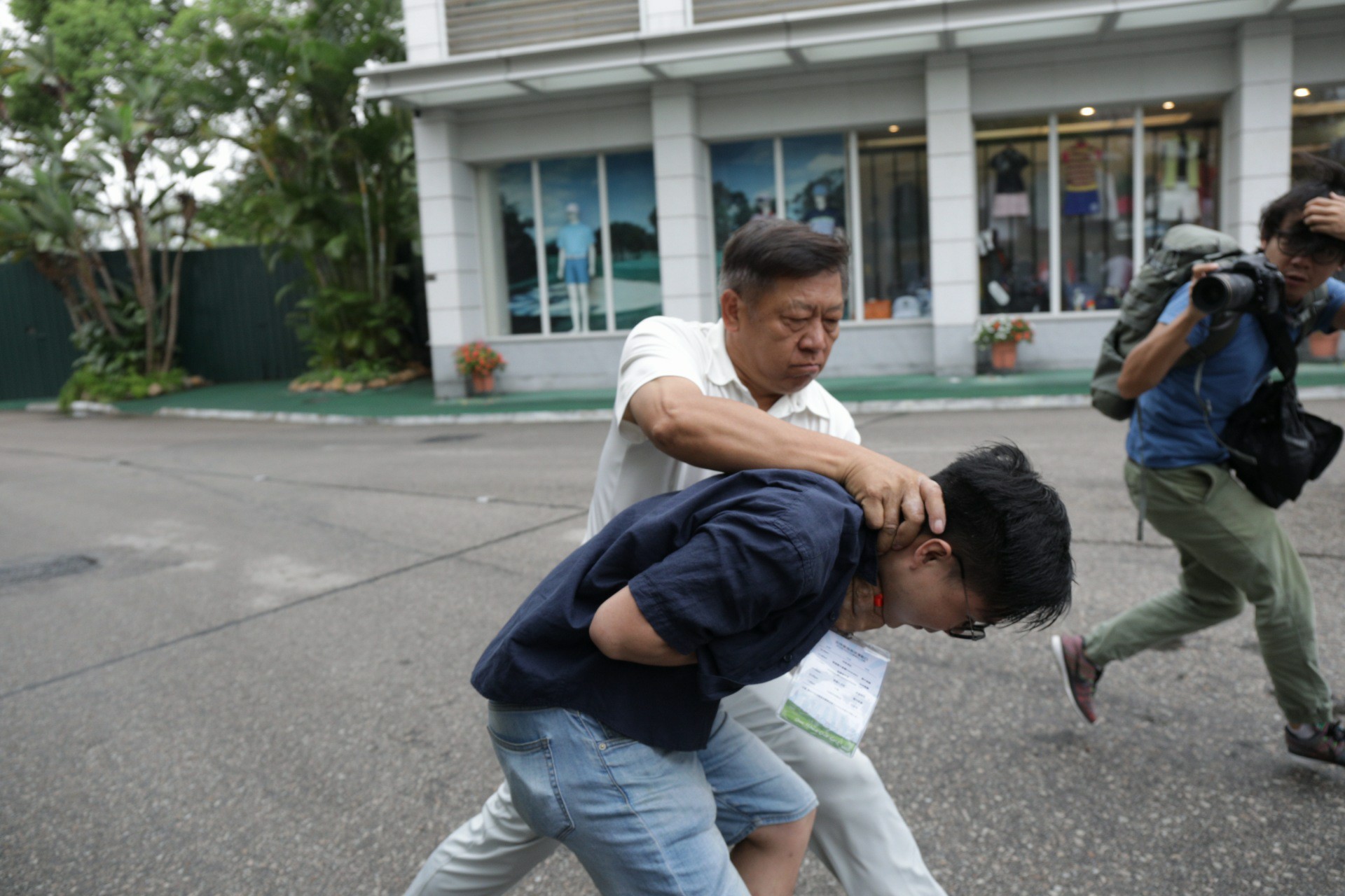 A protestor being grabbed by the neck by a member of the Hong Kong Golfing Alliance. Photo via Facebook.