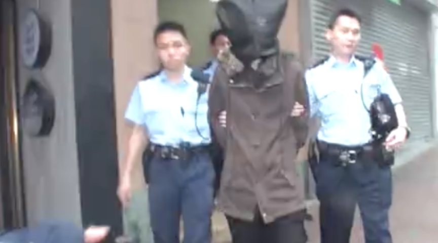 The unnamed 23-year-old suspect in the brutal killing of a dog is escorted by Hong Kong police. Via Apple Daily (screen grab)