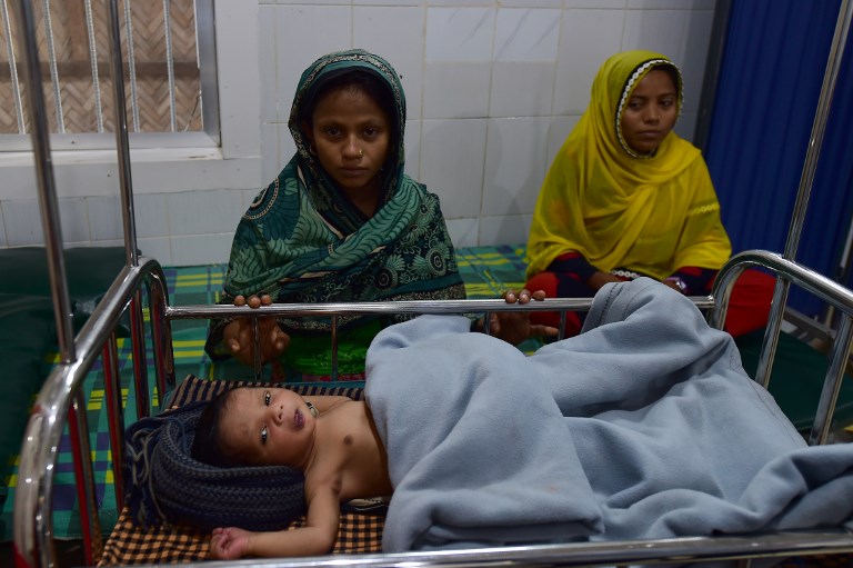 This photograph taken on April 9, 2018, shows a Rohingya mother (L) sitting next to her sick child, who is treated at a Doctors Without Borders (MSF) clinic, at Kutupalong refugee camp in Bangladesh’s Ukhia district.  / AFP PHOTO / MUNIR UZ ZAMAN / 