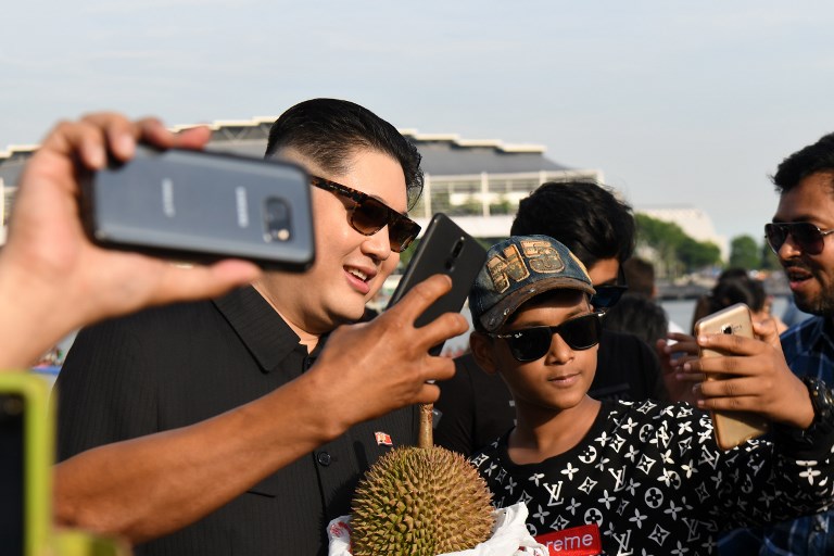 A Kim Jong Un impersonator poses for a selfie with tourists at Merlion Park in Singapore on May 27, 2018. Image: AFP / Roslan Rahman