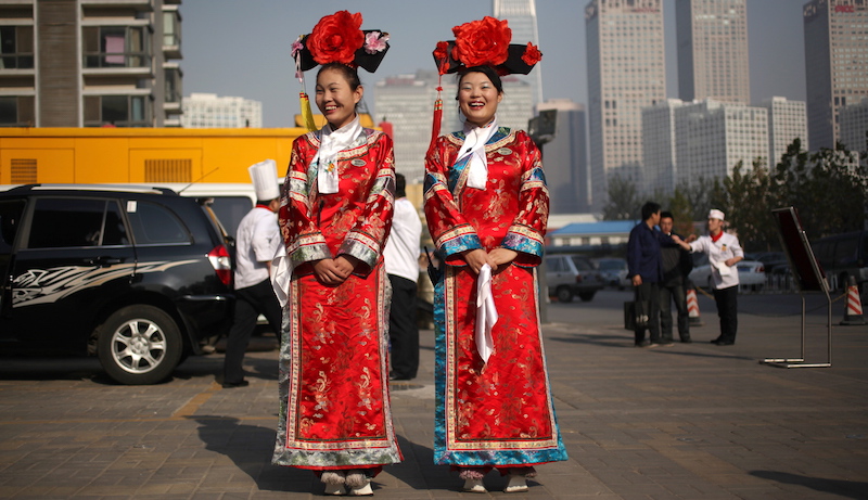 Waitresses dressed up in Qing dynasty costumes share a light moment while waiting to welcome customers outside a Chinese restaurant in Beijing, China, 14 November 2011. The Qing Dynasty was the last dynasty of China, they ruled from 1644 to 1912 and were Manchurians. Photo: How Hwee Young/epa