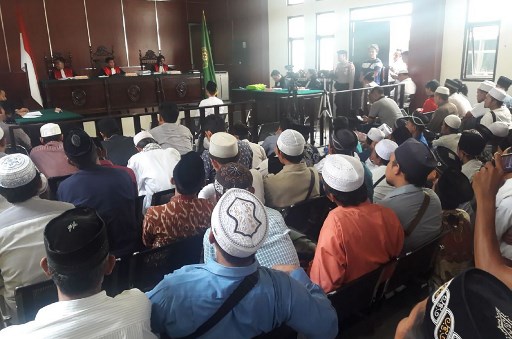 Arnoldy Bahari (middle C), charged with blasphemy and hate speech, sits in front of judges during a court hearing in Pandeglang on April 30, 2018. 
An Indonesian was jailed for five years April 30 for a Facebook post deemed offensive to Islam, his lawyer said, the latest conviction under the country’s controversial electronic information law.
 / AFP PHOTO / –
