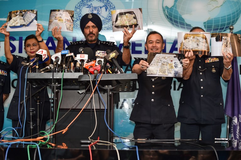 Members of the Malaysian Police’s Commercial Crime Investigation Department (CCID) hold up pictures of seized items while addressing media in Kuala Lumpur on June 27, 2018.
Items seized from six premises linked to ousted Malaysian leader Najib Razak, including cash, a vast stash of jewellery and luxury handbags, are worth up to 273 million USD, police said on June 27. / AFP PHOTO / Mohd RASFAN