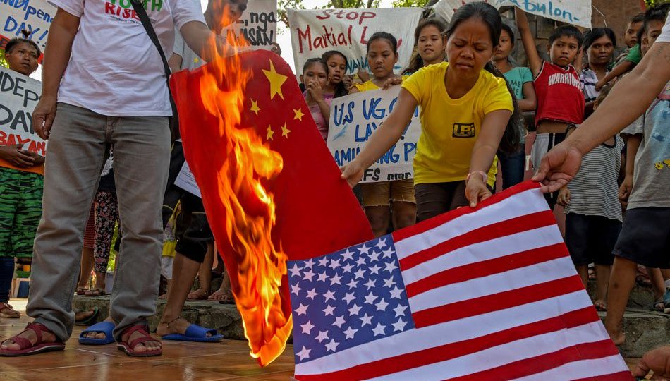 Protesters burn the flags of the United States and the People’s Republic of China during an Independence Day rally in Cagayan de Oro on Tuesday. Photo via ABS-CBN News.
