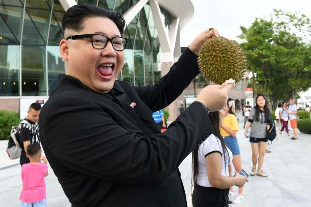 A Kim Jong Un impersonator poses holding a durian fruit in front of the Esplanade theatre in Singapore on May 27, 2018. (AFP)