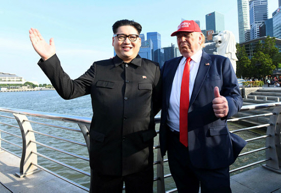 North Korean leader Kim Jong Un impersonator Howard X (L) and Donald Trump impersonator Dennis Alan (R) stand along the Merlion park in Singapore on June 8, 2018. — AFP