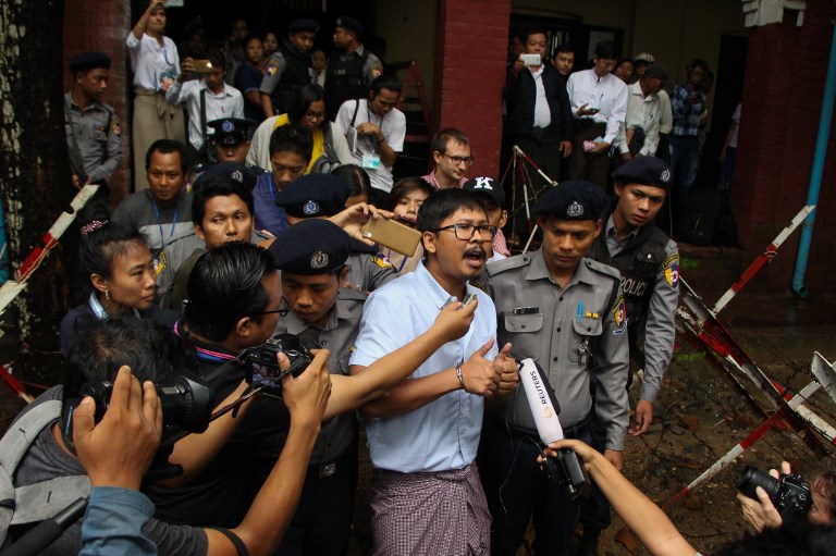 Detained Myanmar journalist Wa Lone (C) speaks to reporters while escorted by police to a court for his ongoing pre-trial hearing in Yangon on July 9, 2018. / AFP PHOTO / STR