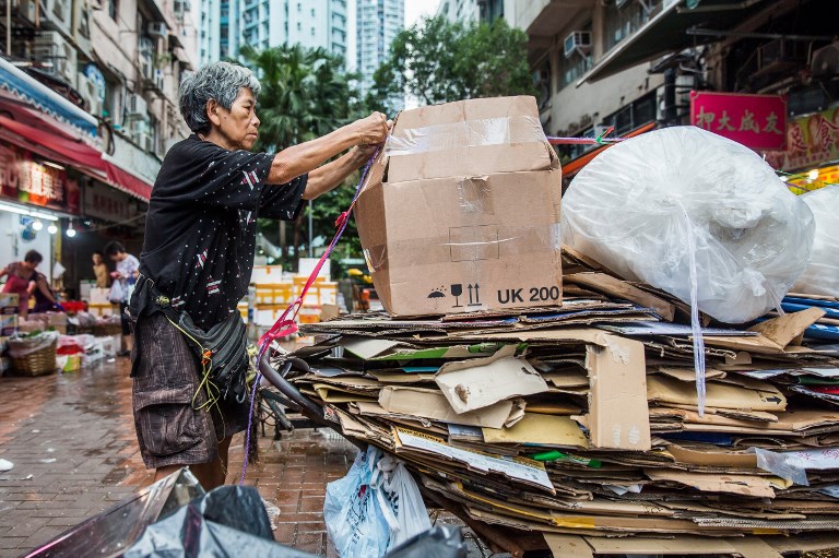 This picture taken on July 20, 2018 shows cardboard collector Au Fung-lan tying down her trolley full of cardboard before making her way to a recycling depot in the Kwai Fong district of Hong Kong.
Her fingers are bent from 20 years of collecting cardboard from Hong Kong’s streets, but Au Fung-lan says she has no desire to give up the gruelling work. At 67-years-old she is one of around 2,900 collectors, mainly women over the age of 60, whose frail figures are a familiar sight, guiding trolleys loaded with cardboard through a city clogged with traffic and people. / AFP PHOTO / Isaac LAWRENCE
