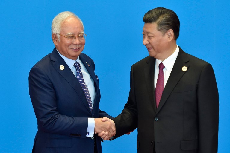 Malaysia’s Prime Minister Najib Razak (L) shakes hands with China’s President Xi Jinping during the welcome ceremony for the Belt and Road Forum, at the International Conference Center in Yanqi Lake, north of Beijing, on May 15, 2017. / AFP PHOTO / POOL / Kenzaburo FUKUHARA