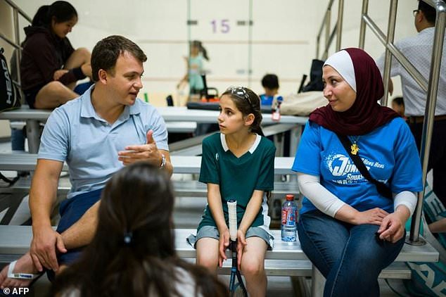 In this photo taken on August 2, 2018, Clayton Kier (L), executive director of Squash Dreamers, a US NGO based in Jordan, and team coach Reem Niaz (R), a refugee from Damascus, speak with Syrian squash player Sabah Husryeh (C), 11, during the Hong Kong Junior Squash Tournament at the Cornwall Street Park Squash Centre in Hong Kong. Three young Syrian squash players, aged between 11 and 13, are part of a new team called Squash Dreamers, made up of displaced Syrian youngsters who were forced to flee their war-torn homeland.
Anthony WALLACE / AFP