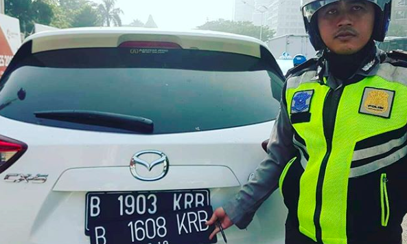 A Jakarta traffic police officers showing a car with two license plates to cheat the city’s odd-even rule. Photo: Instagram/@tmcpoldametro