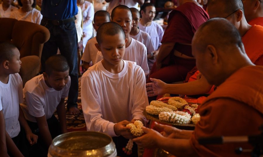 Members of the “Wild Boars” football team hand flower garlands to Buddhist monks during a ceremony to mark the end of their retreat as novice monks at the Wat Phra That Doi Tung temple in the Mae Sai district of Chiang Rai province on August 4, 2018.
The Thai boys freed from a flooded cave in a rescue bid that gripped the world left the Buddhist monastery 11 days after ordaining as novice monks to honour a diver who died in the mission to save them. / AFP PHOTO / Lillian SUWANRUMPHA