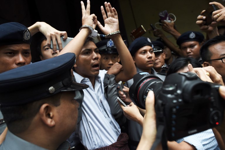 Myanmar journalist Kyaw Soe Oo (C) is escorted by police after being sentenced by a court to jail in Yangon on Sept. 3, 2018. / AFP PHOTO / Ye Aung THU