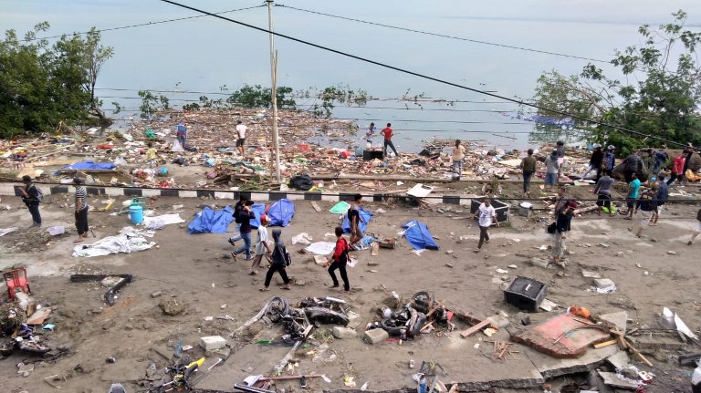 People walk past dead bodies (blue cover) a day after an earthquake and a tsunami hit Palu, on Sulawesi island on September 29, 2018.
Rescuers scrambled to reach tsunami-hit central Indonesia and assess the damage after a strong quake brought down several buildings and sent locals fleeing their homes for higher ground. Photo: Ola Gondronk/AFP