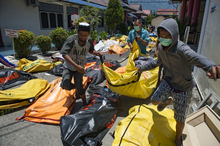 Family members carry the body of a relative to the compounds of a police hospital in Palu, Indonesia’s Central Sulawesi on September 30, 2018, following a strong earthquake in the area. PHOTO: AFP / BAY ISMOYO