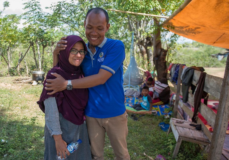 This picture taken on October 1, 2018 shows Azwan hugging his wife Dewi Prasasti in front of their house and family members in Palu, Central Sulawesi, after an earthquake and tsunami hit the area on September 28.
It was two agonizing days of searches through makeshift morgues and hospitals before Azwan found his wife Dewi alive and well after she was swept away in the tsunami that crashed into the Indonesian city of Palu. Photo: Bay Ismoyo/AFP