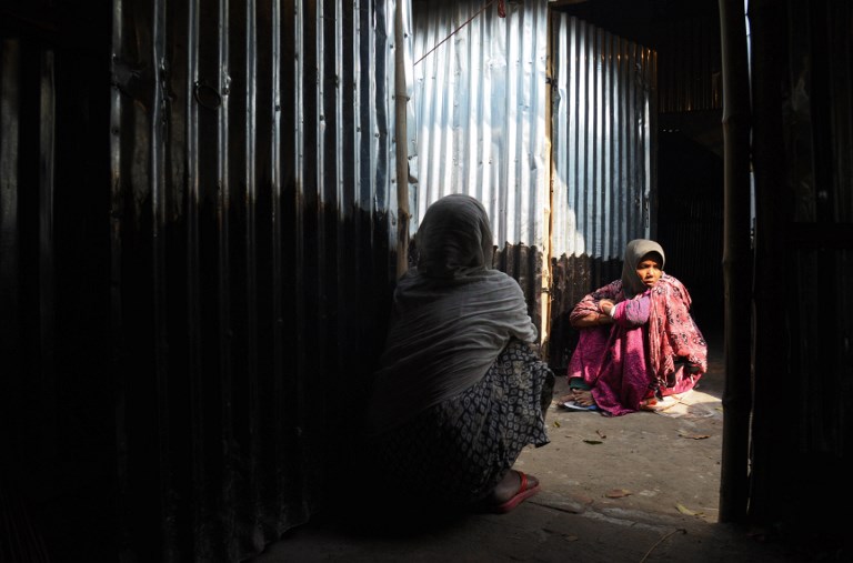 In this file photo taken on January 19, 2018 Rohingya refugees rest on temporary shelters near the village of Baruipur, some 55km south of Kolkata. / AFP PHOTO / Dibyangshu SARKAR
