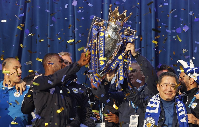 In this file photo taken on May 16, 2016 Leicester City’s Thai owner and chairman Vichai Srivaddhanaprabha (R), Leicester City’s Italian manager Claudio Ranieri (2R) and Leicester City’s English defender Wes Morgan (2L) hold up the Premier league trophy to fans as the Leicester City team celebrate in Victoria Park, after taking part in an open-top bus parade through Leicester, to celebrate winning the Premier League title on May 16, 2016. – A helicopter belonging to Thai tycoon Vichai Srivaddhanaprabha crashed on October 27, 2018 near the stadium of his UK football club Leicester City. The identities of the pilot and any passengers on board have not yet been confirmed. It is also not yet known if anyone on the ground was injured. (Photo by ADRIAN DENNIS / AFP)