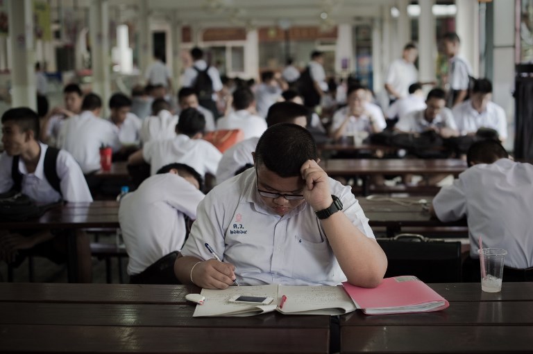 A student does homework in the canteen of a high school in Bangkok, June 18, 2015. Photo:  Nicolas Asfouri/ AFP