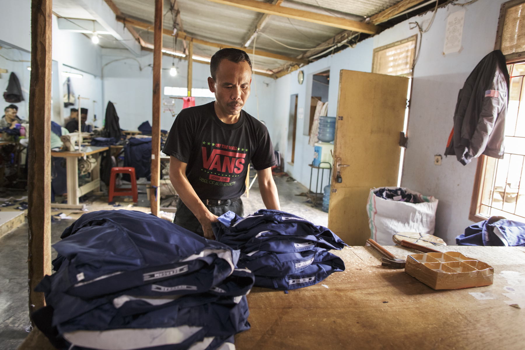 Sodikin, a 34-year-old man with a psychosocial disability, at his workplace. Sodikin, who was shackled for more than eight years in a tiny shed outside the family home in Cianjur, West Java, now works in a clothing factory stitching buttons onto boys’ school uniforms. Photo: Andrea Star Reese for Human Rights Watch