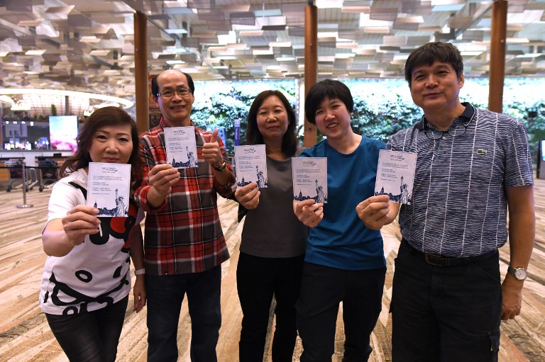 Singaporean William Chua (R) with family members, all passengers of SIA’s inaugural non-stop flight to New York, pose with souvenir cards after their their check-in at Changi International Airport in Singapore on October 11, 2018. Photo: Roslan Rahman / AFP