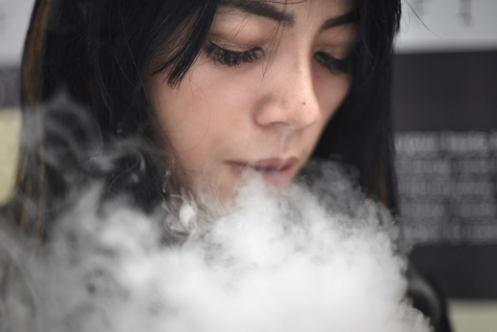 Silvia Arnisa exhales vapors for a photograph while working as a promoter at the 2018 Jakarta Vape Fest in Jakarta. Photo: Reynold Sumayku