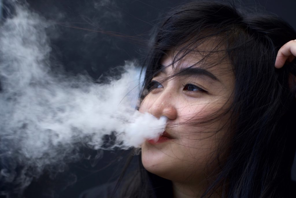 Thara Aprilia poses for a picture with her e-cigarette while working at a well-known brand's counter at the 2018 Jakarta Vape Fest in South Jakarta. Photo: Reynold Sumayku