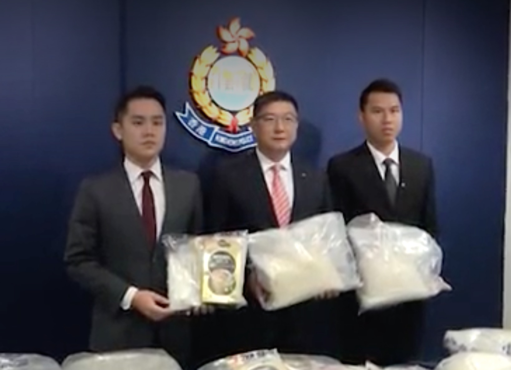 Anti-drug police celebrating their massive bust the best way they know how: getting photographed holding big bags of drugs. Screengrab via Apple Daily video.