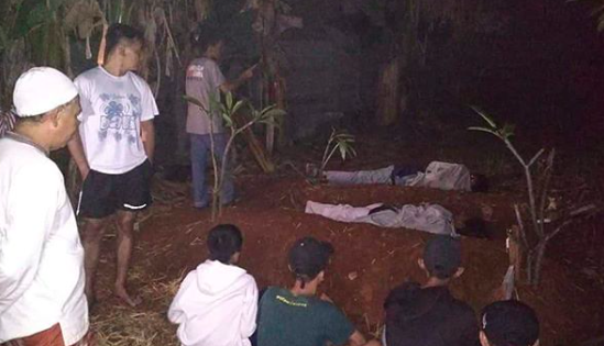 Locals watch on as two young boys in Depok are being made to sleep in a graveyard as punishment for their attempt at a spooky prank. Photo: Instagram / @infodepok_id