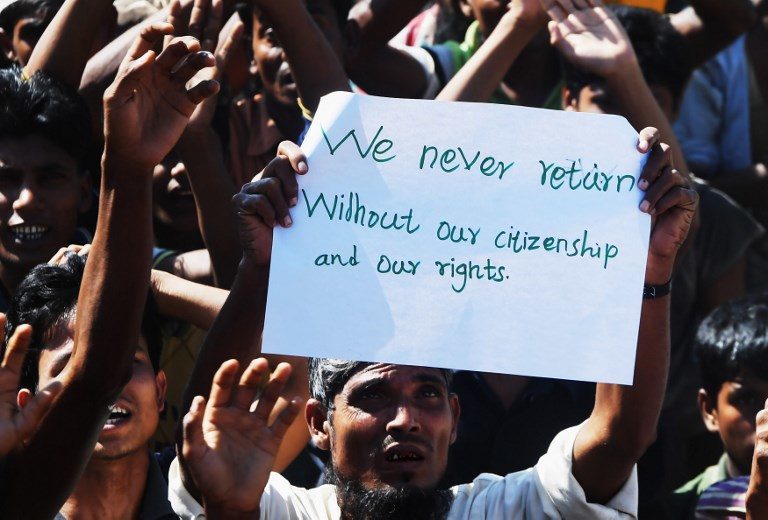 A Rohingya refugee carries a placard that says “We never return” at a protest against a disputed repatriation programme at the Unchiprang refugee camp near Teknaf on November 15, 2018. (Photo by Dibyangshu SARKAR / AFP)