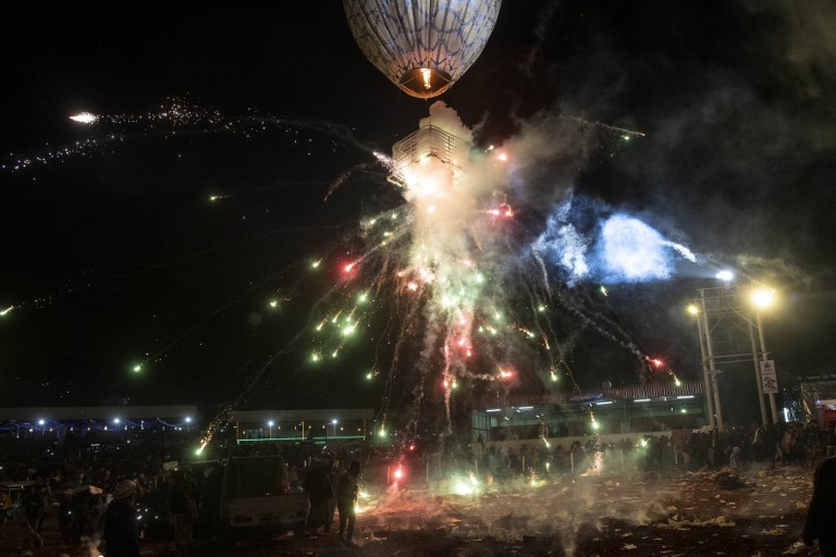 This picture taken on November 14, 2018 shows participants releasing a hot-air balloon carrying small lanterns during the Tazaungdaing Lighting Festival at Taunggyi in Myanmar’s northeastern Shan State. – Brightly coloured balloons with hundreds of homemade fireworks woven into their frames are sent soaring into the night sky, showering down cascades of sparks onto adoring crowds in the annual Taunggyi fire balloon festival. (Photo by Ye Aung THU / AFP)