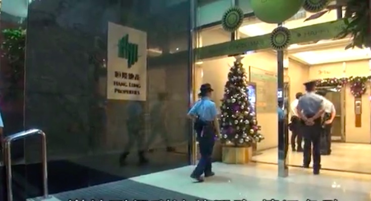 Police walking into the commercial building in Tsim Sha Tsui where Franklin Li’s plastic surgery clinic is located. Screengrab via Apple Daily video.
