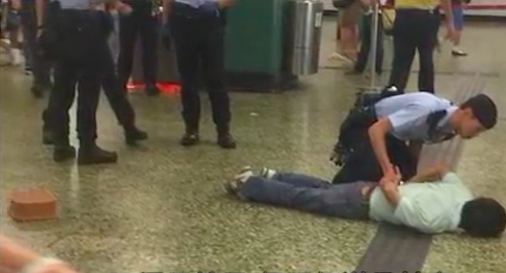 Police subdue a 55-year-old man who was shot after waving a blade at two officers during a stop and search at Sham Shui Po MTR station. just on the left-hand side of the screen is a basket covering the blade that was reportedly used. Screengrab via Apple Daily video.