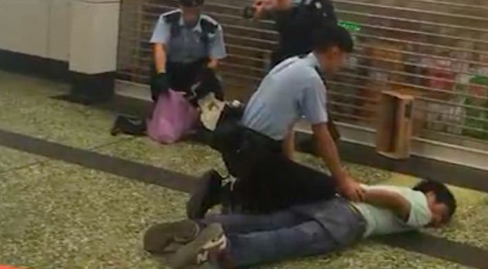 Police subdue a 55-year-old man who was shot after waving a blade at two officers during a stop and search at Sham Shui Po MTR station. Screengrab via Apple Daily video.