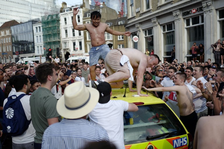 People dance on a NHS ambulance as fans celebrate in the street beside Borough Market after England’s win over Sweden in the Russia 2018 World Cup quarter-final football match, in London on July 7, 2018. (Photo by Tolga AKMEN / AFP)