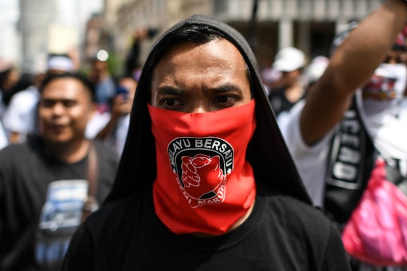 A protester covers his face with a banner reading “Malay Unite” during a rally organised by Muslim politicians against the signing of the UN anti-discrimination convention (ICERD) at Merdeka Square in Kuala Lumpur on December 8, 2018. (Photo by Mohd RASFAN / AFP)