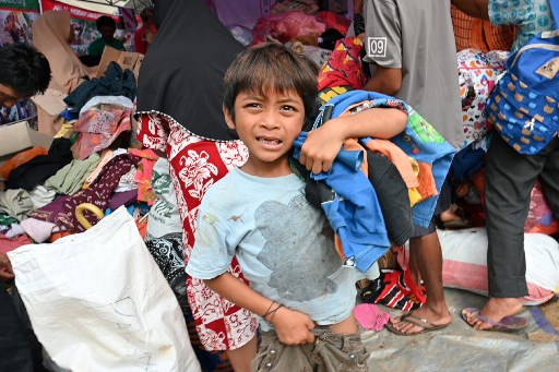 A boy carries donating clothing at a help centre in Citangkil village in Sumur, Pandeglang, Banten province on December 25, 2018, three days after a tsunami – caused by activity at a volcano known as the “child” of Krakatoa – hit the west coast of Indonesia’s Java island.  Adek Berry / AFP